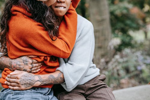 Free Faceless multiracial couple hugging on bench in park Stock Photo