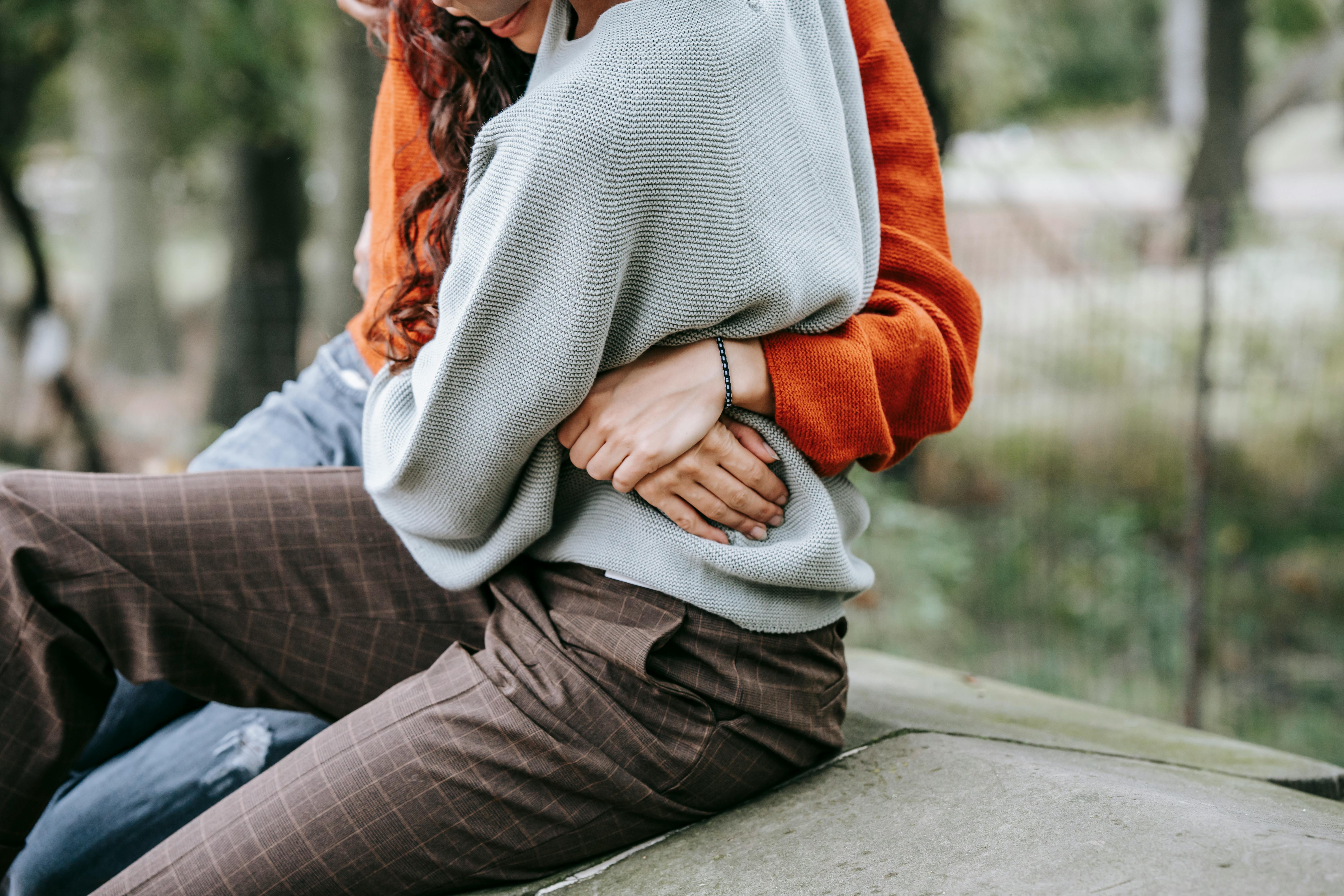 faceless couple hugging on stone in park