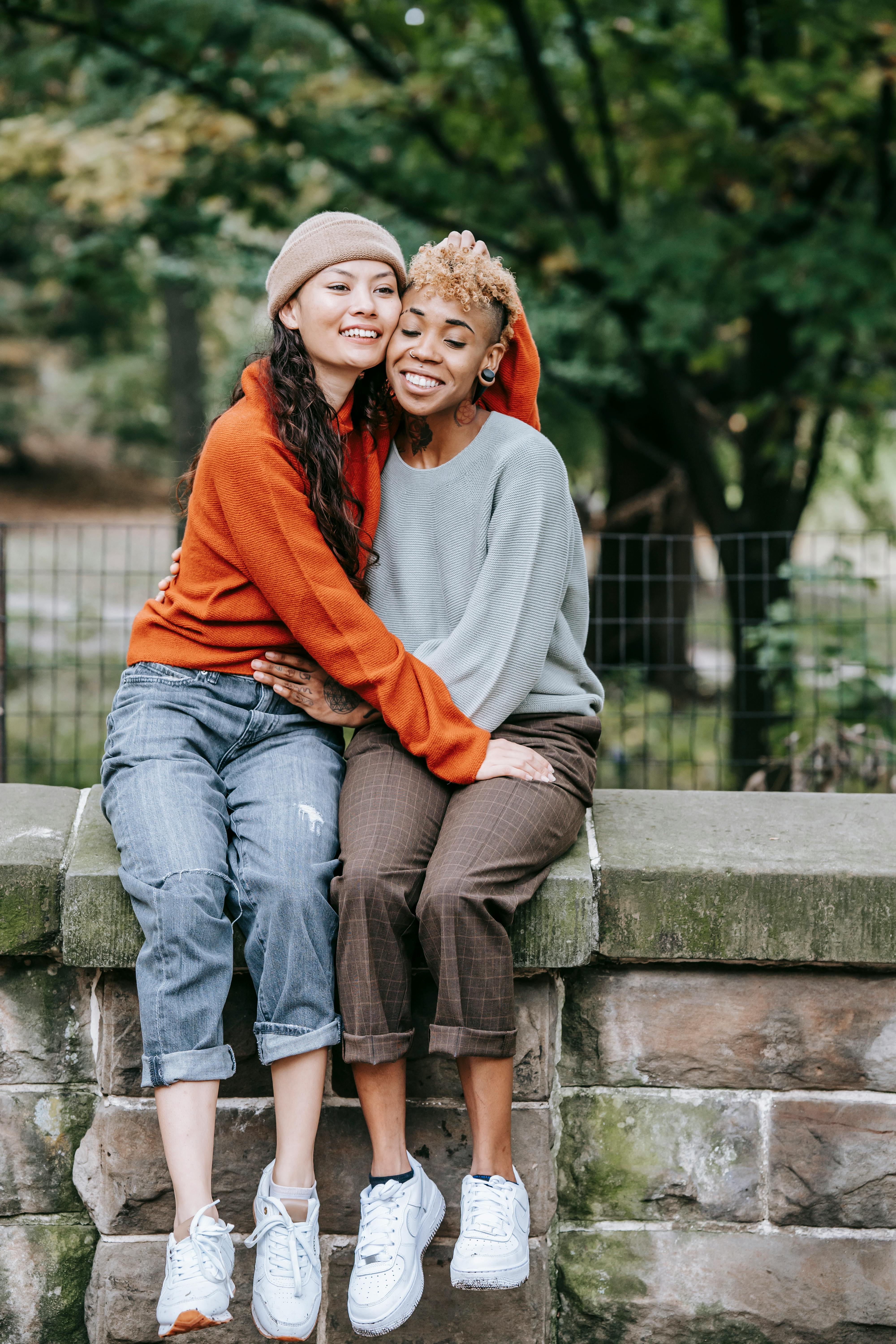 diverse lesbian couple sitting on street and hugging in daytime