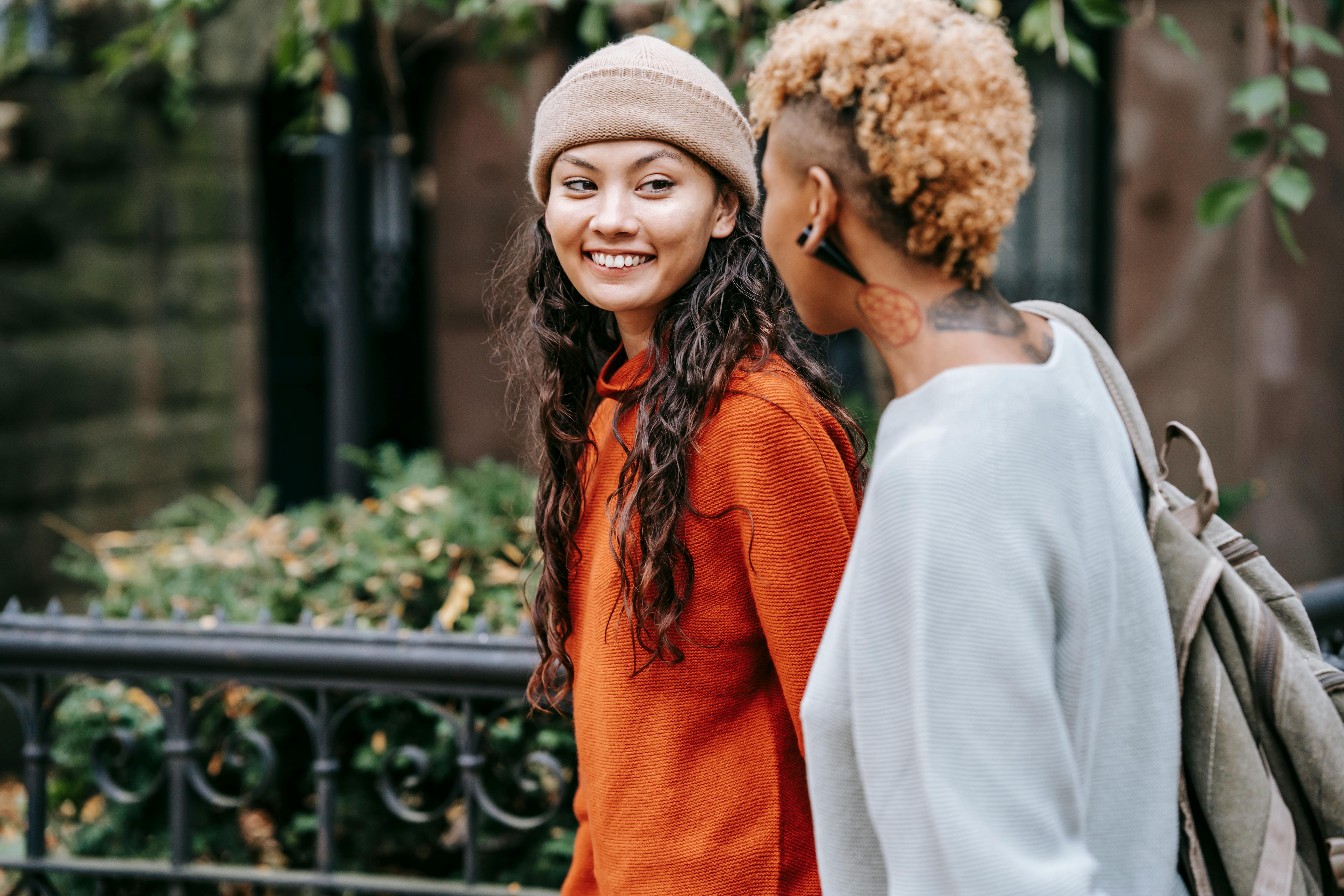 young informal female talking with girlfriend while walking together