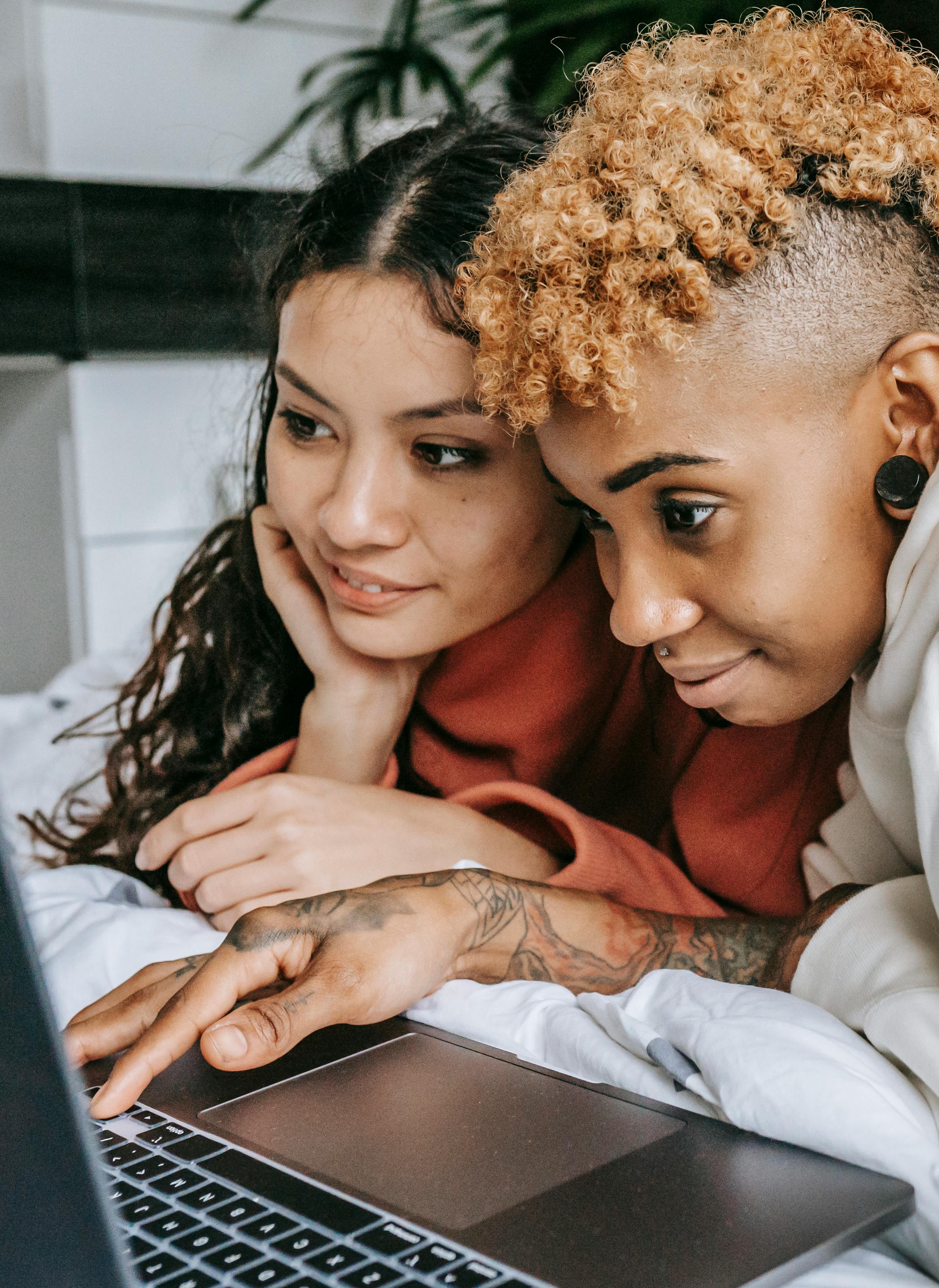 smiling multiracial couple surfing laptop together while resting on bed