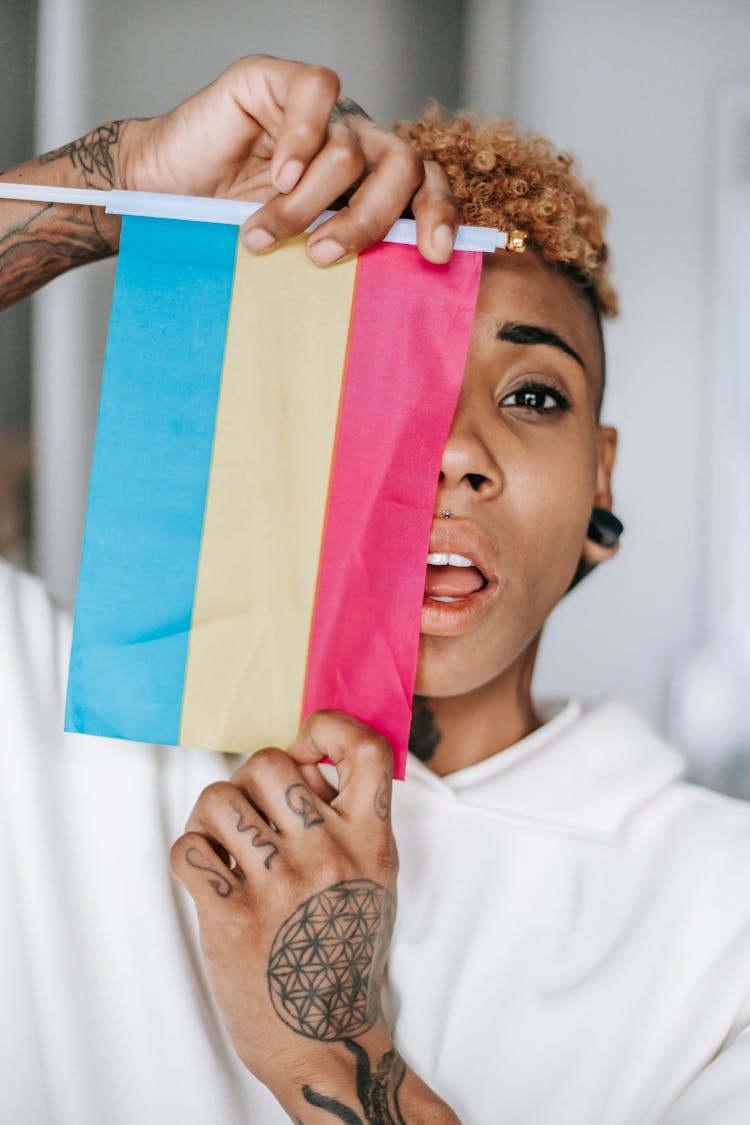 Stylish Black Woman With Tattoo Hiding Face Behind Pansexual Pride Flag