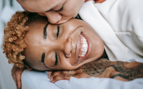 Free Close-up of a joyful moment between two adults. One is being kissed on the cheek while smiling happily. Stock Photo