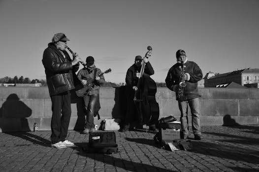 A group of musicians performing with instruments outdoors in a monochrome setting.