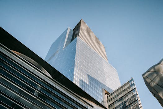 Contemporary glass skyscraper from a low angle against a cloudless sky, showcasing urban architecture.