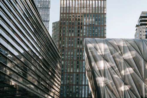 Free Contemporary geometric buildings with glass wall and unusual design located on street in downtown against skyscraper in modern district in city Stock Photo