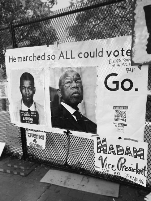 Protest posters honoring leaders and advocating voting rights on a metal fence.