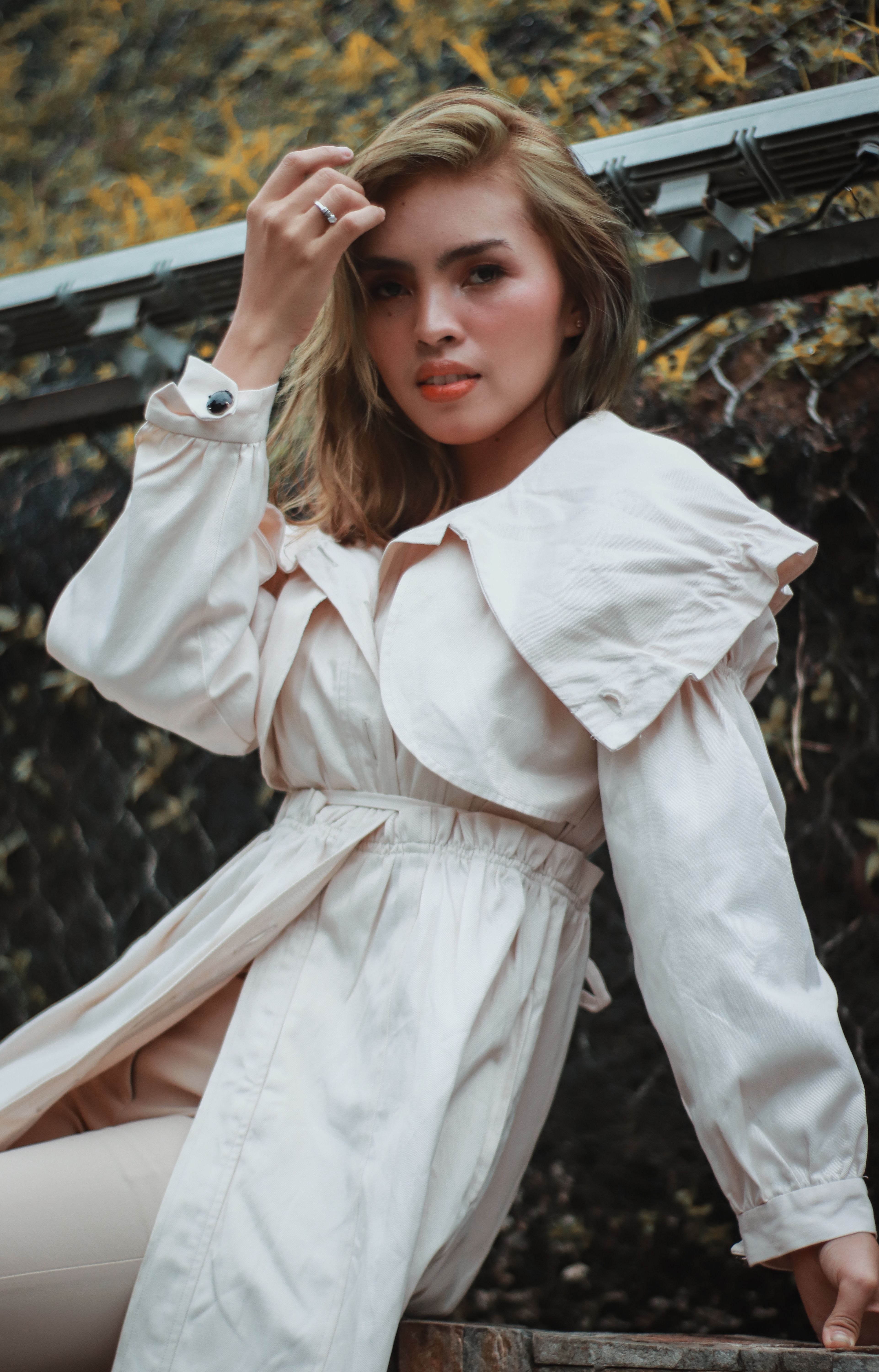 Woman in cream trench coat and white outfit