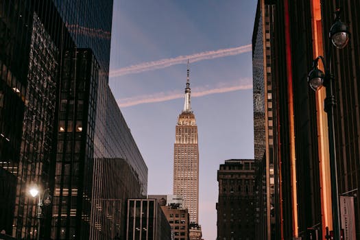 Sunset view of the Empire State Building in New York City, flanked by modern skyscrapers.