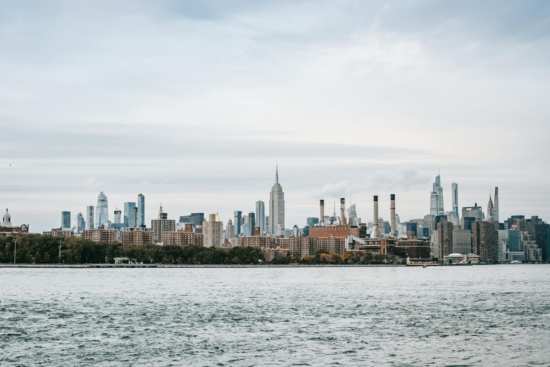 Scenery of New York cityscape with modern urban architecture situated on rippling East River coast on clear weather