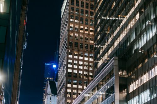 Free From below of high rise towers with lights in windows located in business city district at night Stock Photo