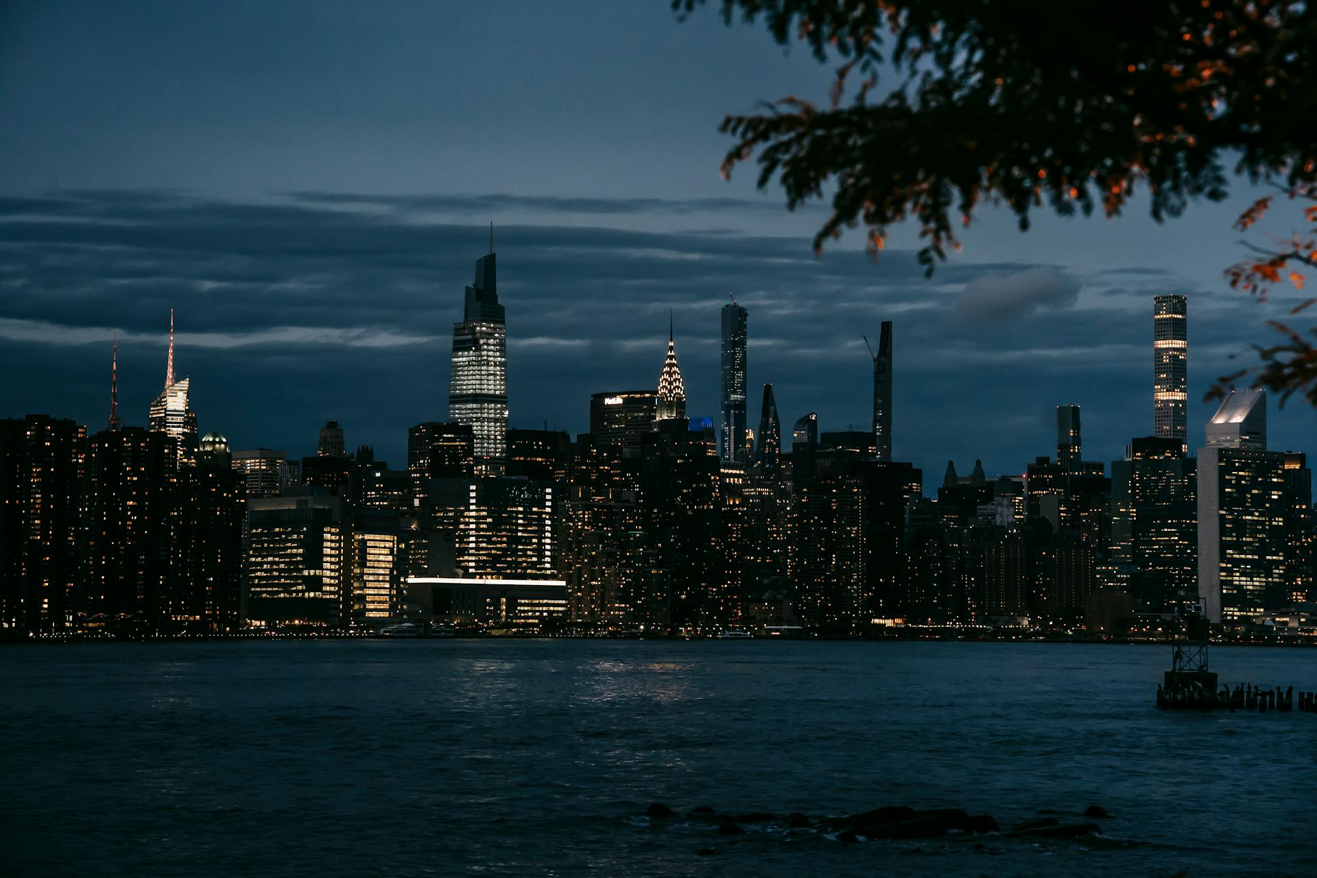 Modern skyscrapers with glowing lights in windows in New York on coast of river