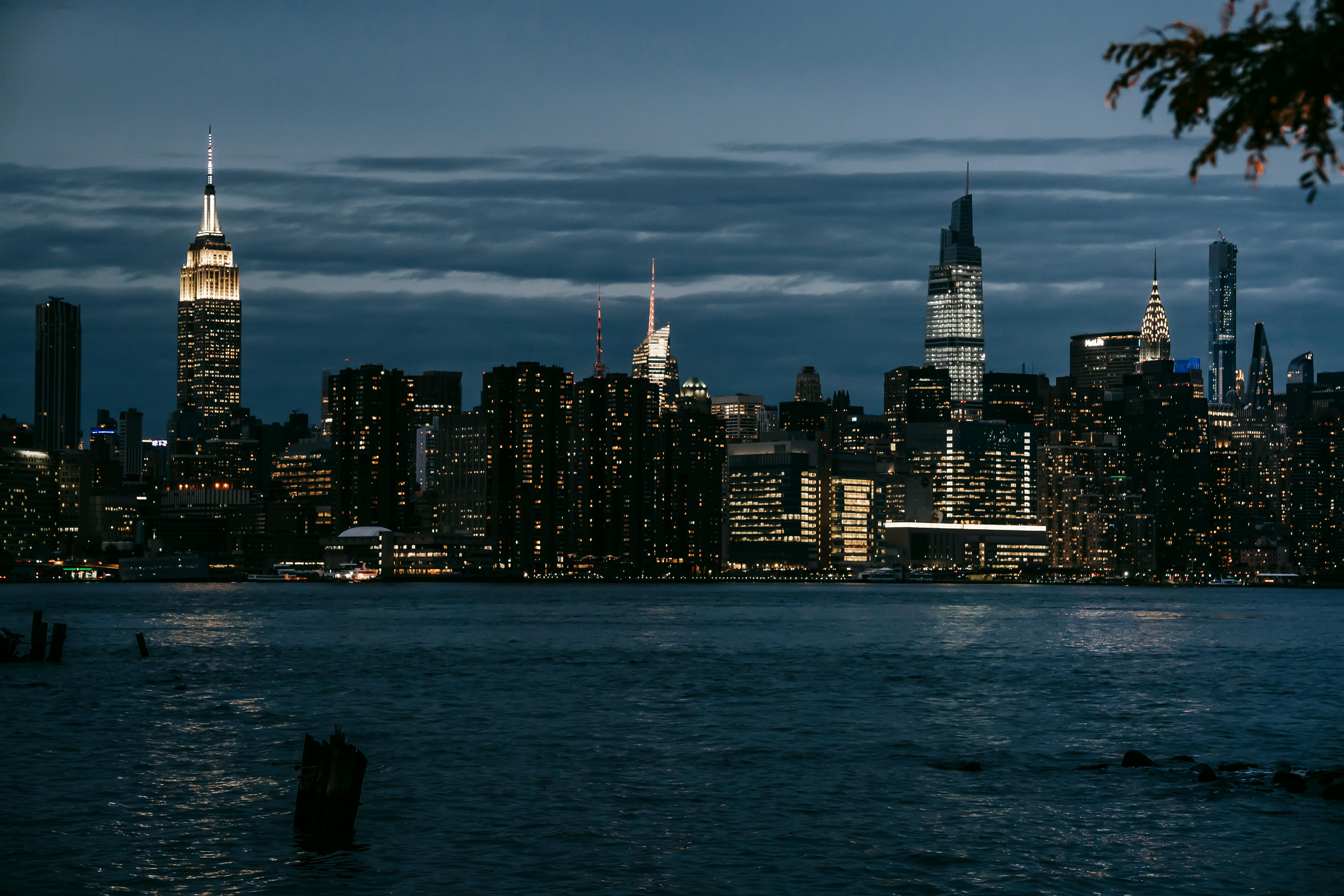 Contemporary illuminated towers located in central district on coast of rippling river in New York at night