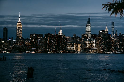 Contemporary illuminated towers located in central district on coast of rippling river in New York at night