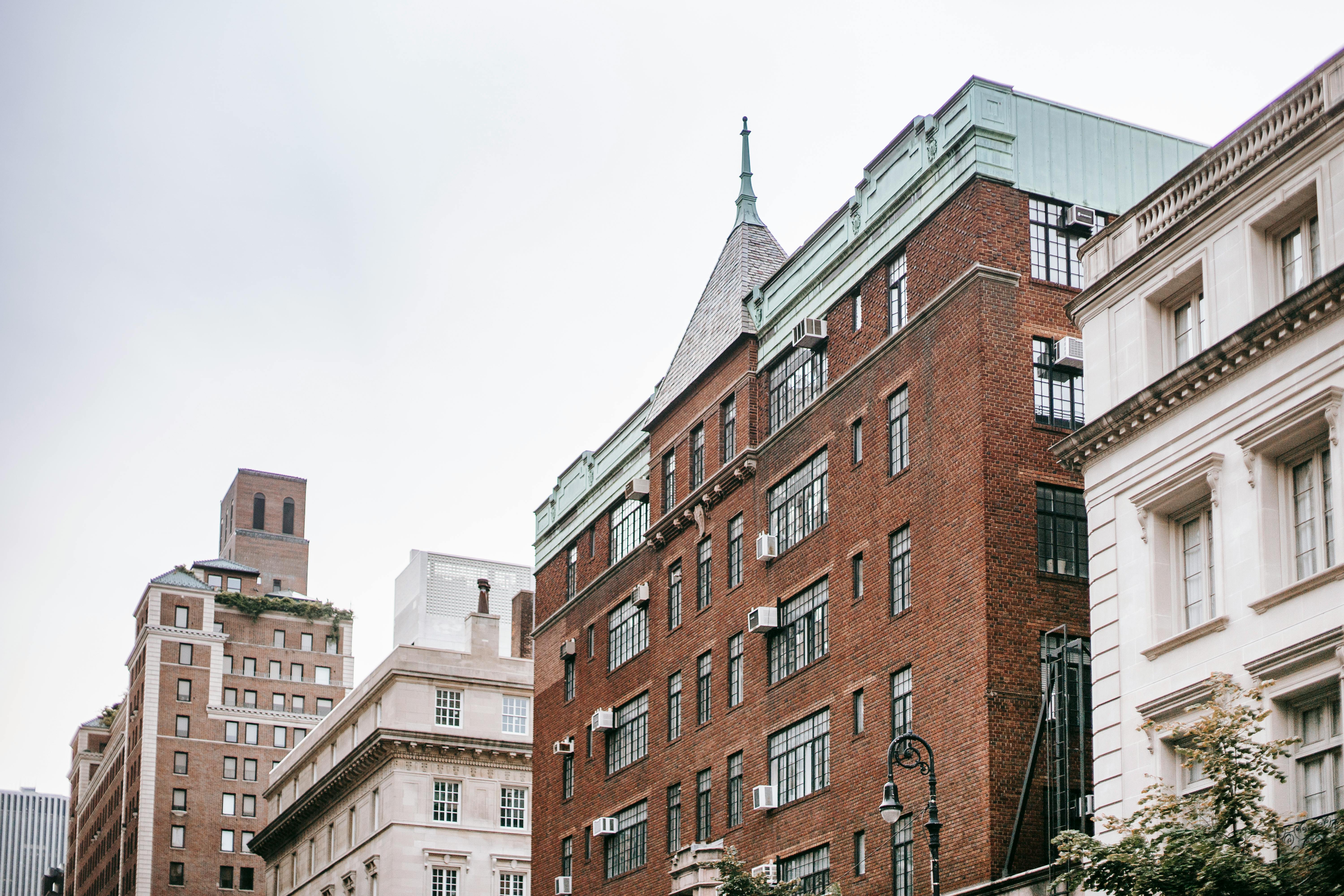 From below of concrete and brick buildings located in residential district of modern city