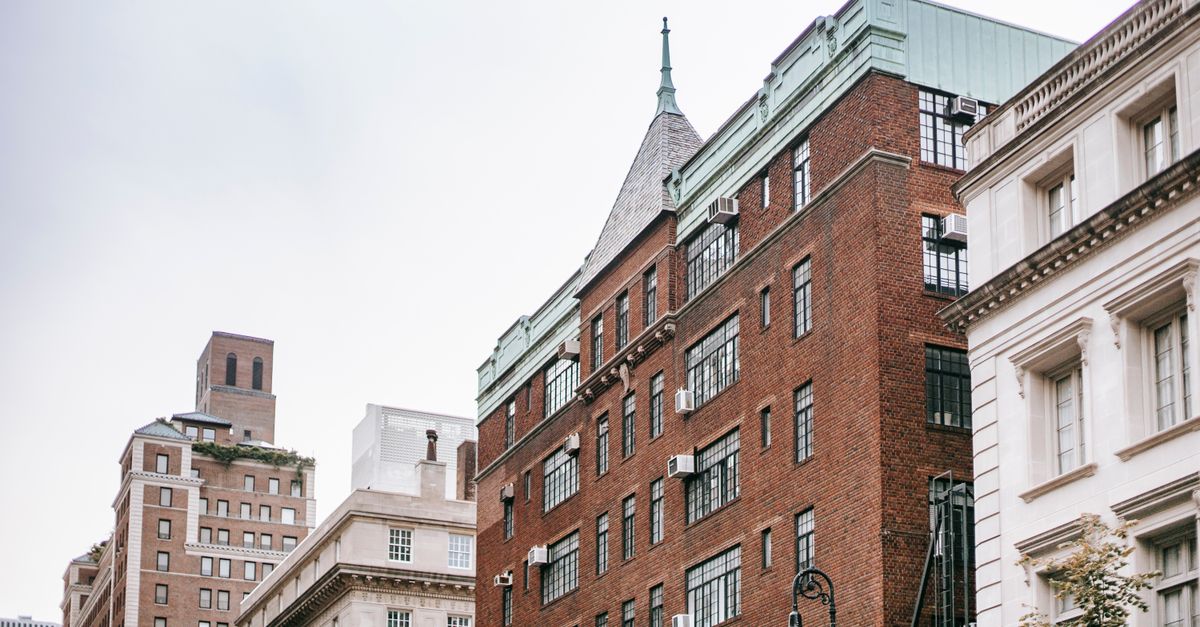 From below of concrete and brick buildings located in residential district of modern city