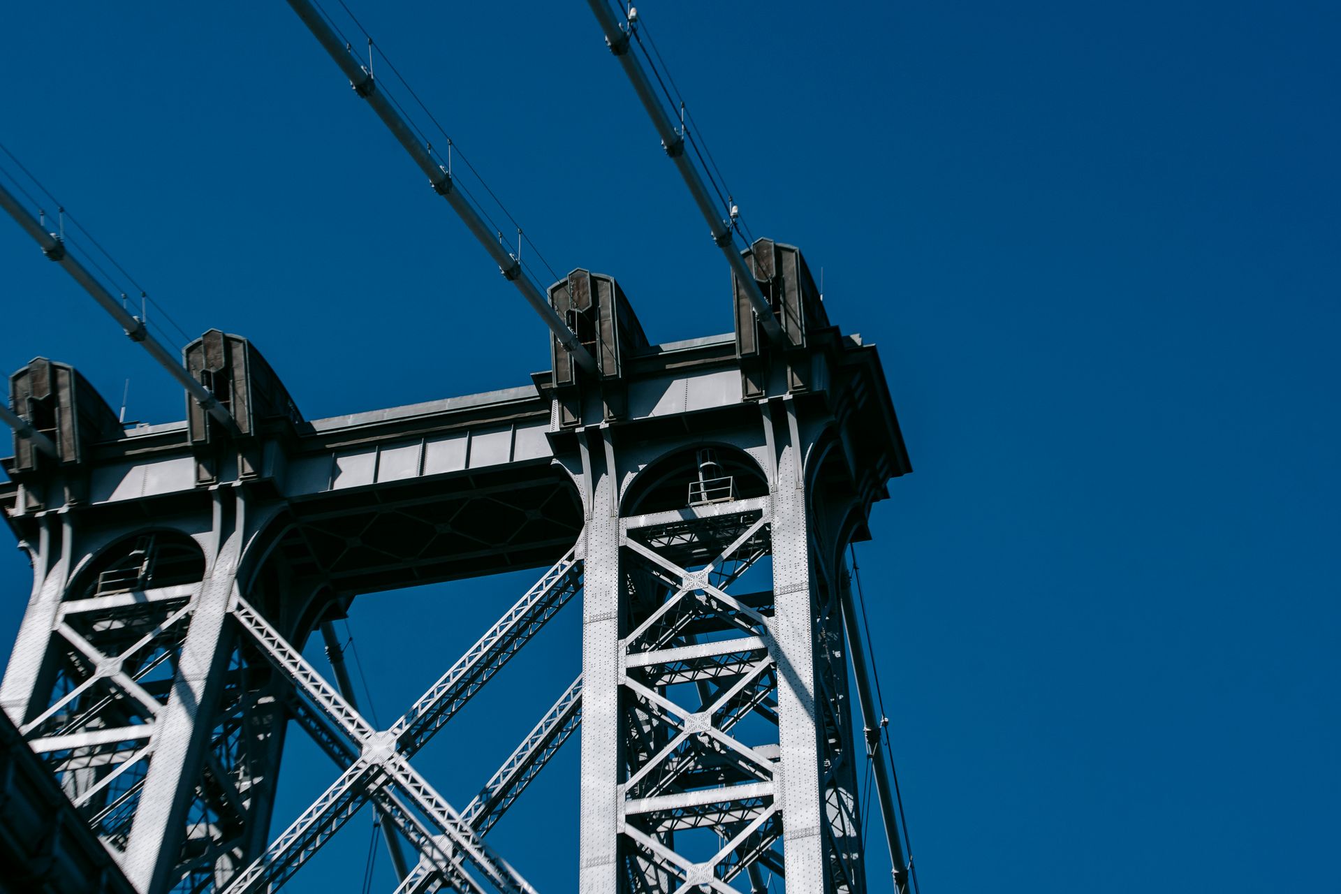 Detailed view of the Williamsburg Bridge structure against a vivid blue sky in New York City.