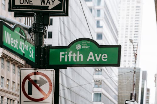 Free Metal post with direction indicator on avenue with high skyscrapers in New York Stock Photo