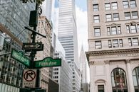 Low angle of road sign on pillar with traffic light located in city on avenue with modern skyscrapers and residential buildings