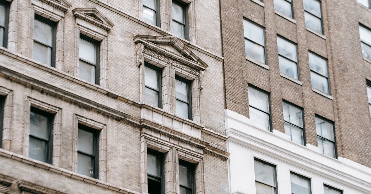 Low angle fragment of exterior of apartment building with windows on gray facade located in city on street in modern district
