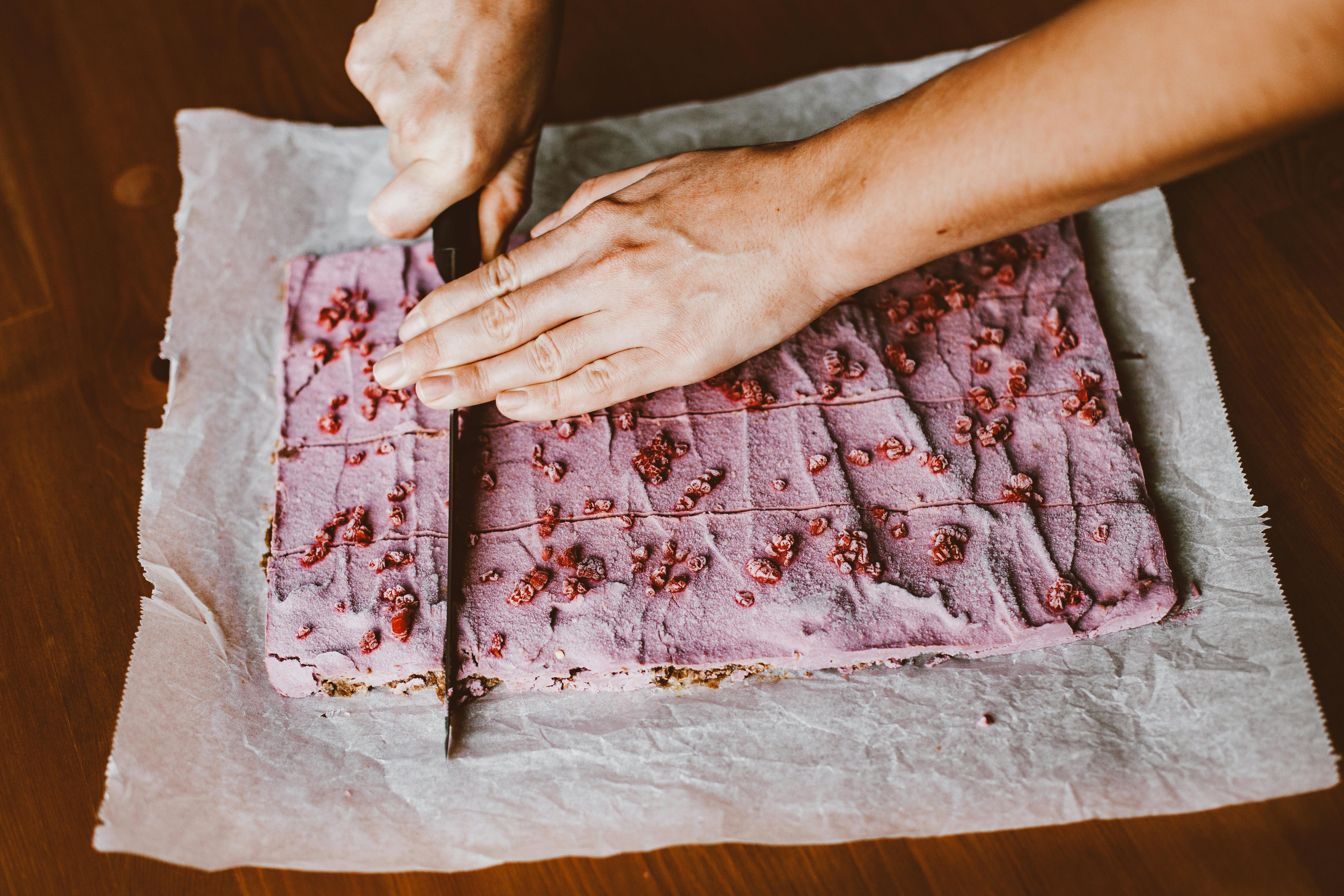 hands cutting pink cake