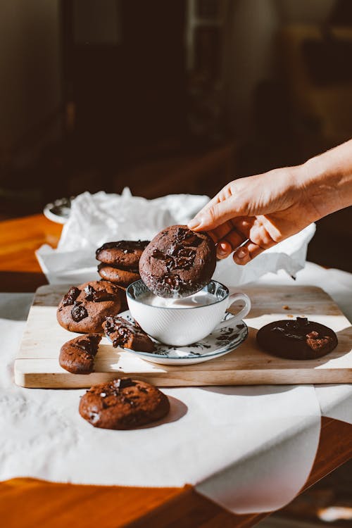 Person Holding Chocolate Chip Cookies near Cup of Milk