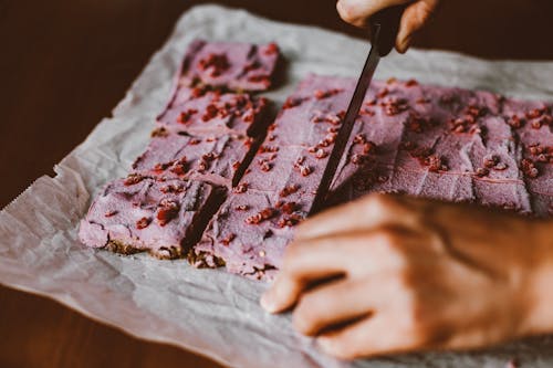 Hands of Person Cutting Pink Cake