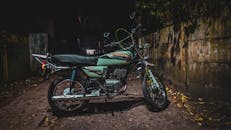 Green and Black Standard Motorcycle Parked Beside Brown Concrete Wall
