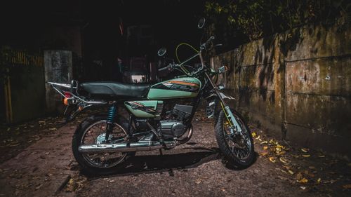 Free Vintage motorcycle parked on a quiet urban street at night, surrounded by trees and buildings. Stock Photo