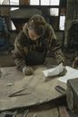 Man in Brown and Black Camouflage Jacket Writing on White Paper