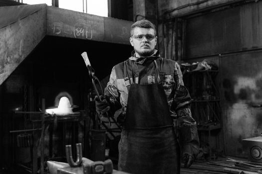A Man in Black Apron Holding Tongs