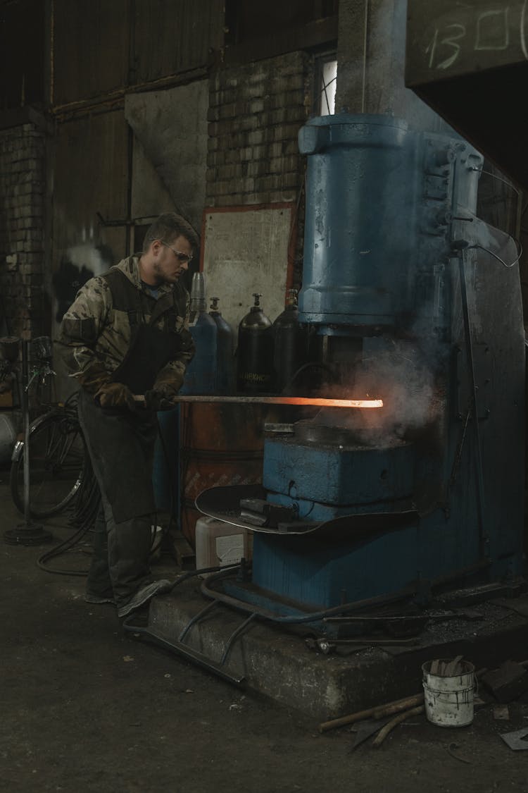 Man Forging Metal Using A Machine