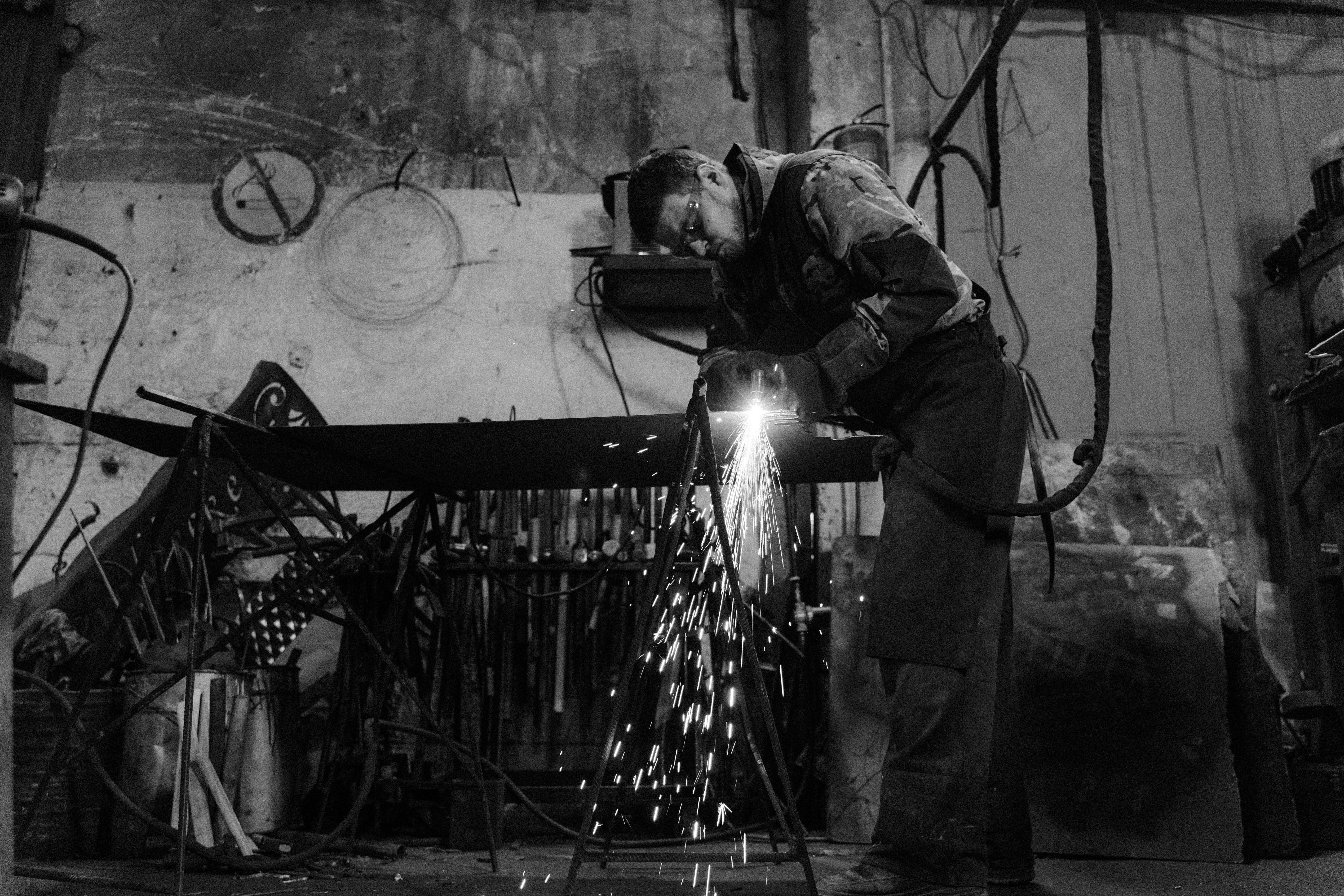 man in safety glasses welding a metal bar