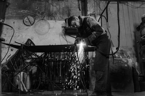 Man in Safety Glasses Welding a Metal Bar