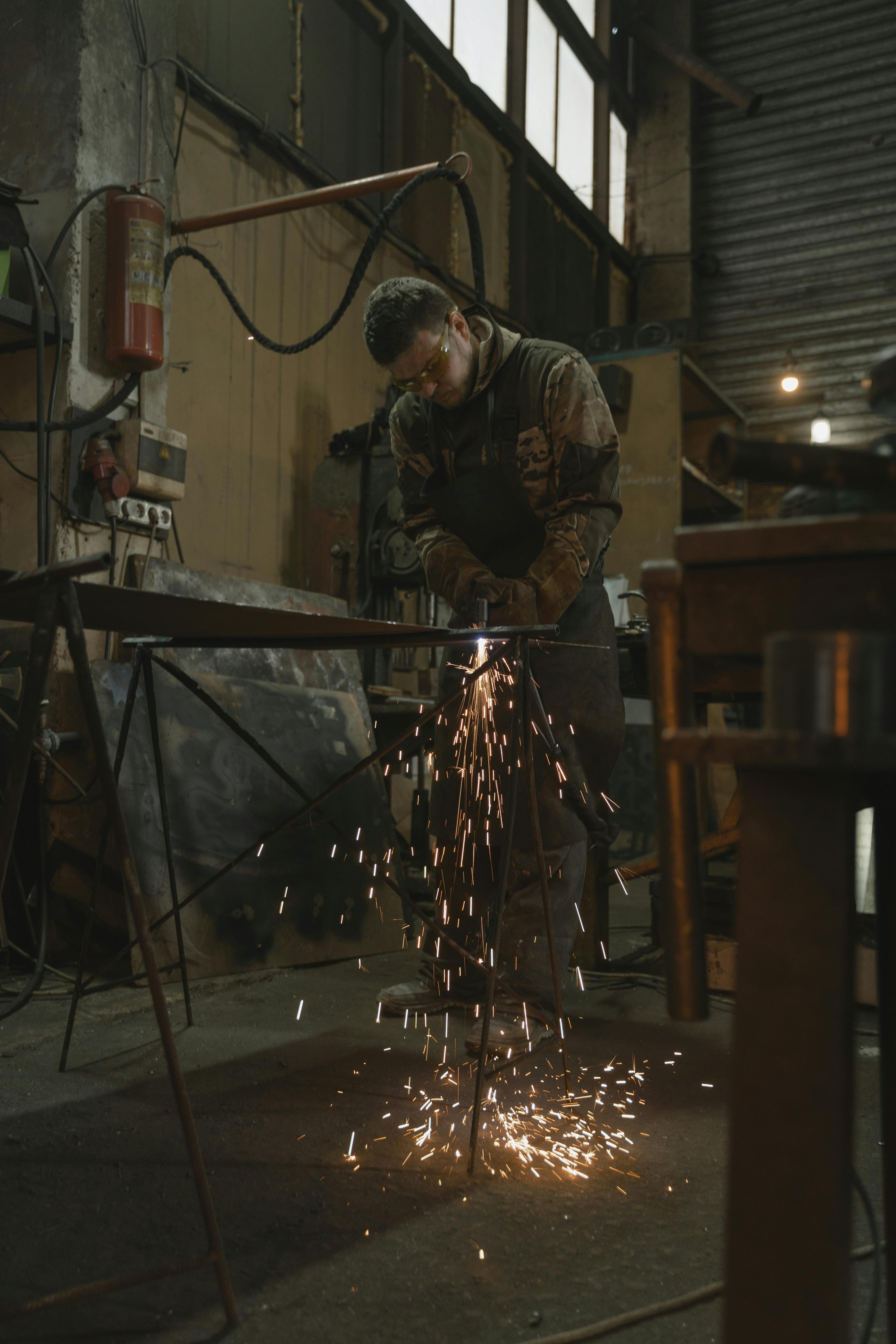 man in safety glasses welding a metal bar