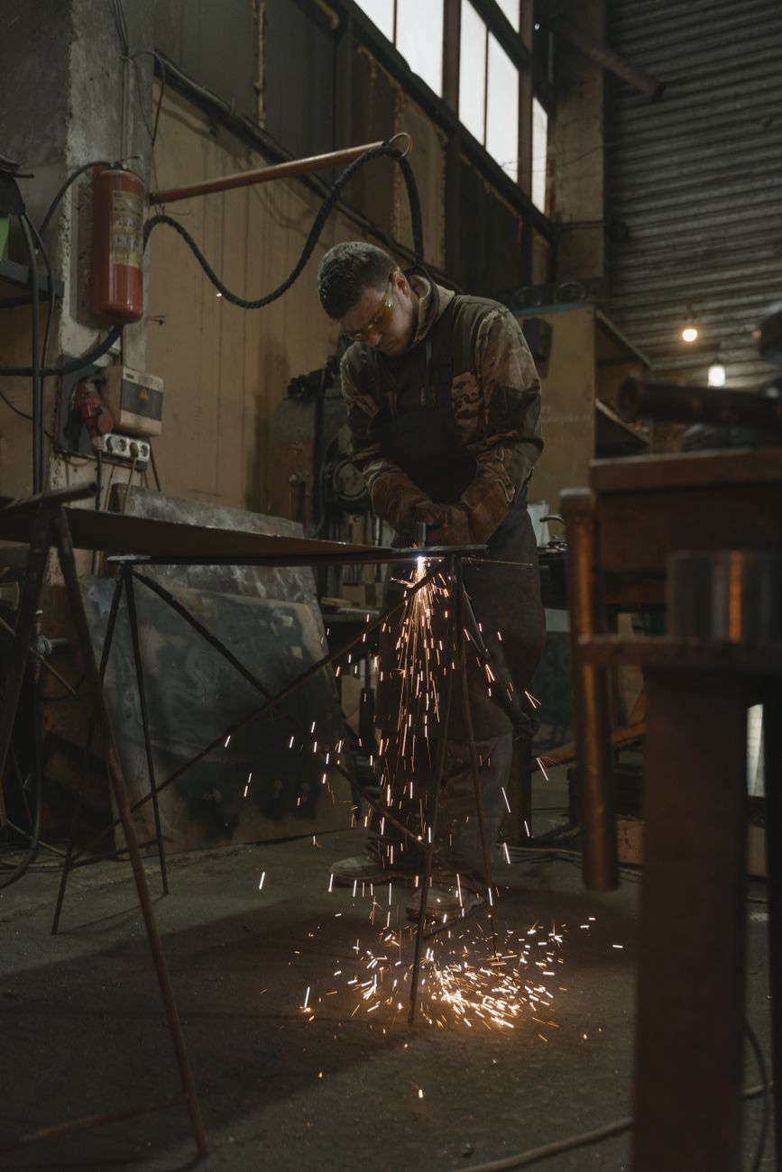 A welder wearing safety glasses works in a factory producing sparks.