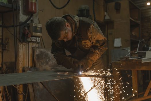 A focused welder in protective gear working with metal, creating vivid sparks in a workshop.