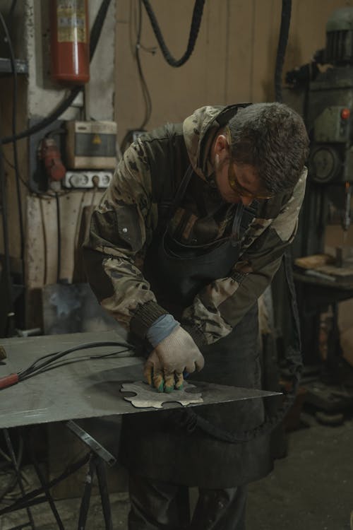 Man in Green Jacket Holding Gray Metal Tool