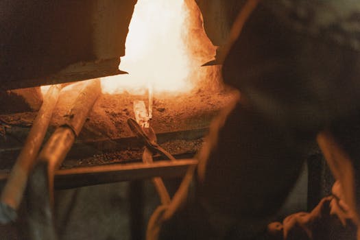 A captivating view of intense heat in a metal forging workshop, showcasing traditional blacksmithing tools and techniques.