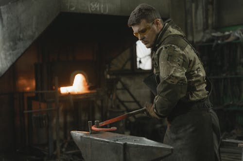 Man in Green Jacket Holding Red Stick