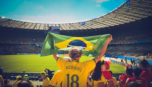 Free Man Raising Brazil Flag Inside Football Stadium Stock Photo