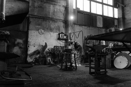 Free A blacksmith uses a grinder in a workshop producing sparks. Industrial setting. Stock Photo