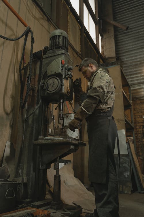 Man in Green and Brown Camouflage Uniform Standing Near Black and Gray Industrial Machine