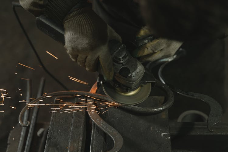 Person In Black Safety Gloves Holding A Grinder