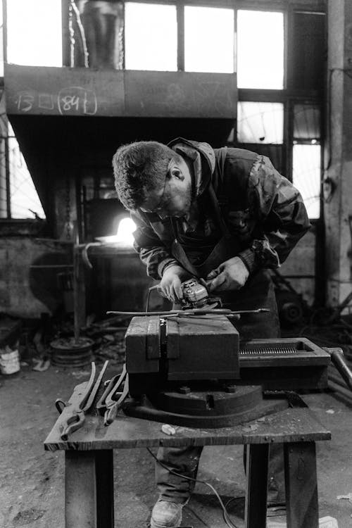 Grayscale Photo of a Man Doing a Metalwork