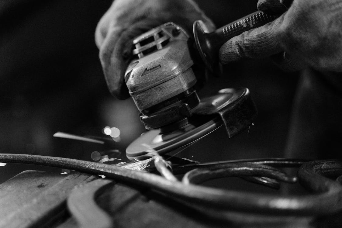 Grayscale Photo of Person Using a Power Tool