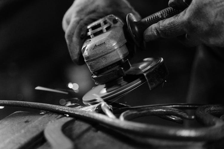 Grayscale Photo Of Person Using A Power Tool