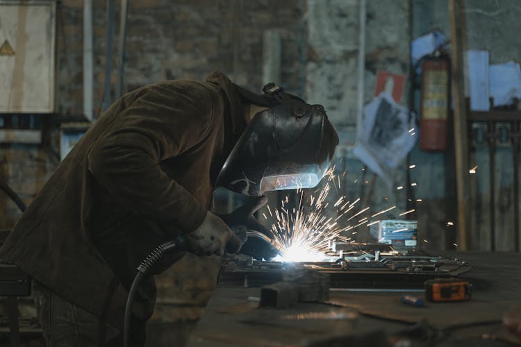 A Person Welding At A Workshop