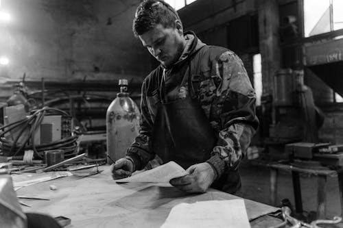 Grayscale Photo of Man Writing on Paper