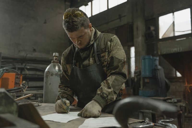 Engineer marking up a drawing in a workshop, photo by Tima Miroshnichenko on Pexels